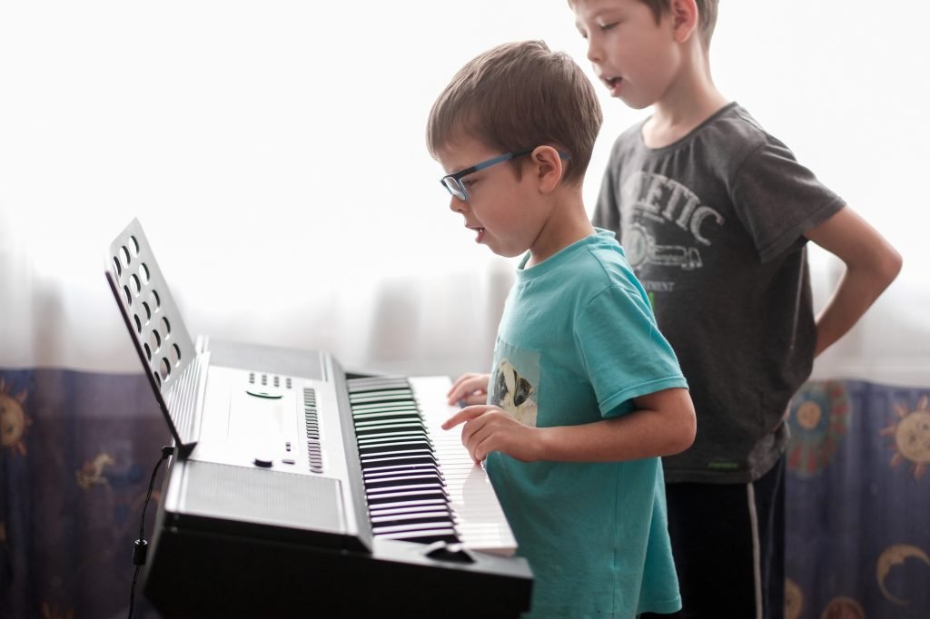 children play digital piano. music lessons at home. Boys playing the synthesizer at home.
