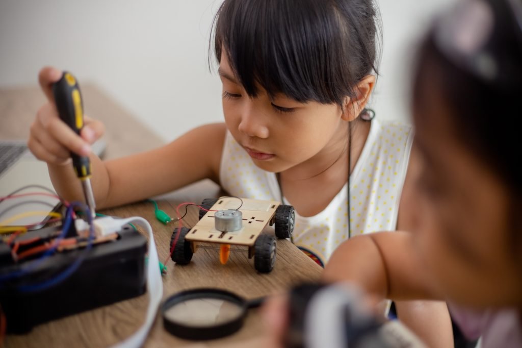 inventive kids learn at home by coding robot cars and electronic board cables in STEM. constructing