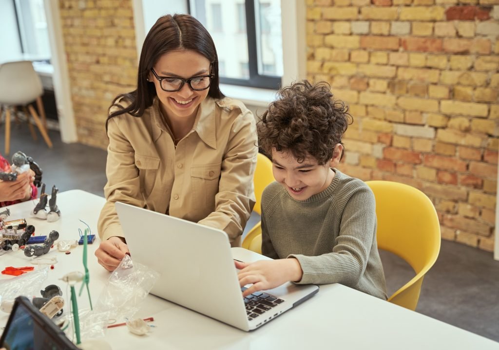 Learning to code. Smiling young female teacher in glasses showing scientific robotics video to